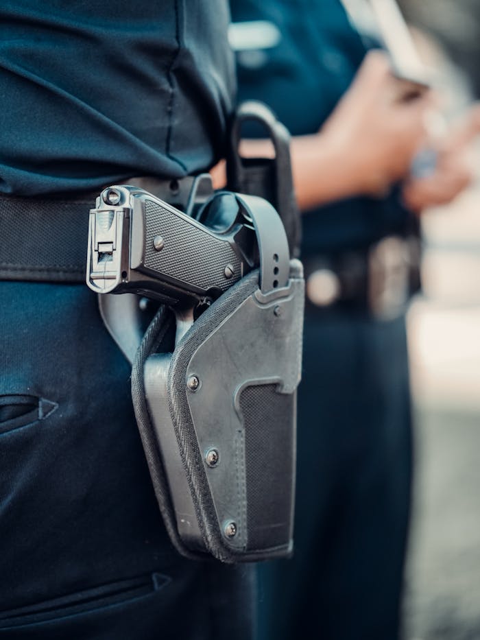 Services Detailed view of a police officer's gun holstered on the belt with blurred background.